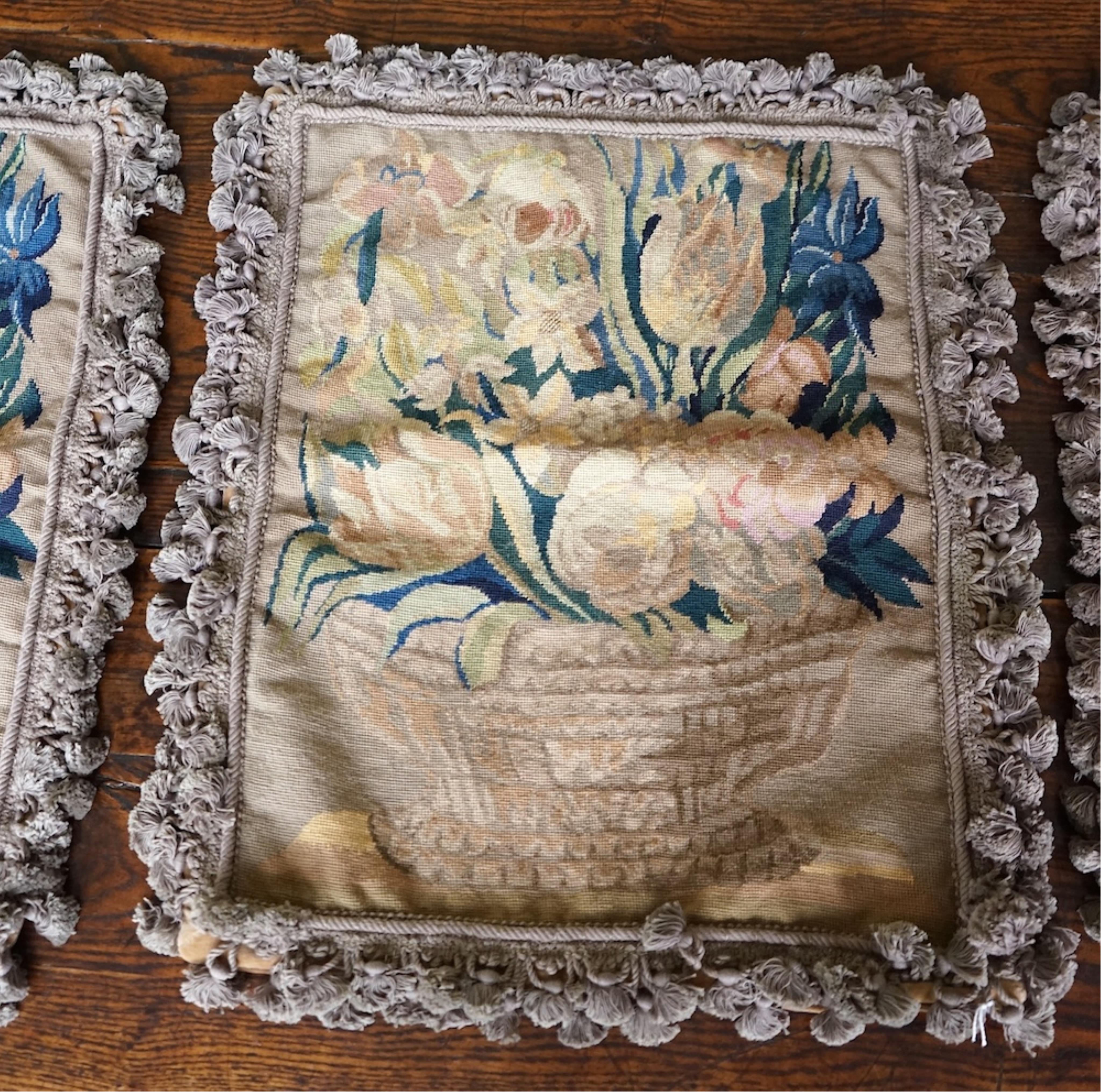 Four large rectangular wool worked cushion covers, with a still life design of a bowl of roses, tulips and daffodils. Embroidered in very muted colours, with ornate tasseled braid and velvet backing. 48cm high x 39cm wid